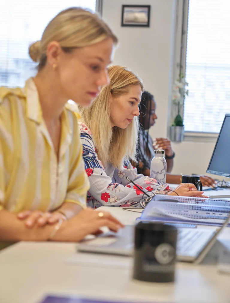 Trois collaboratrices expertes-comptables concentrées à leur bureau dans le cabinet Advyse.